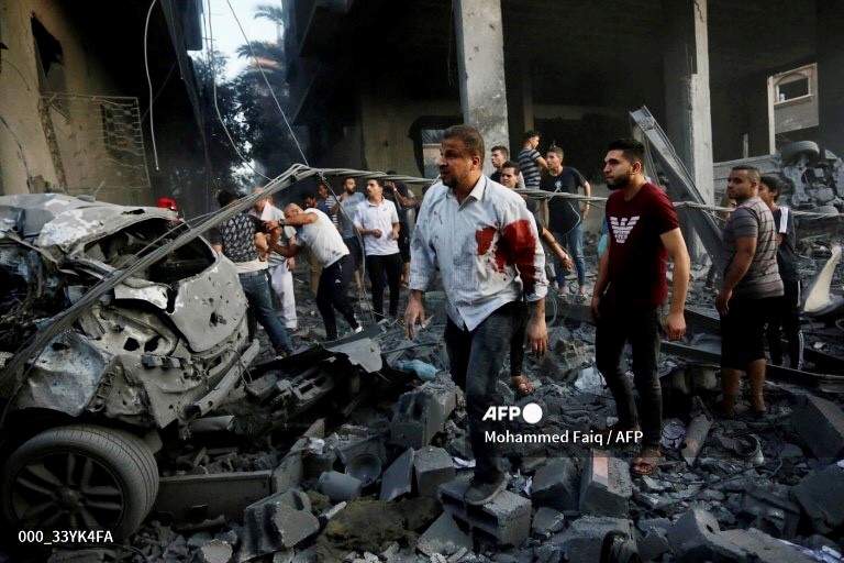 A group of people standing around a destroyed car

Description automatically generated