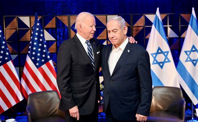 Two men in suits standing in front of flags

Description automatically generated